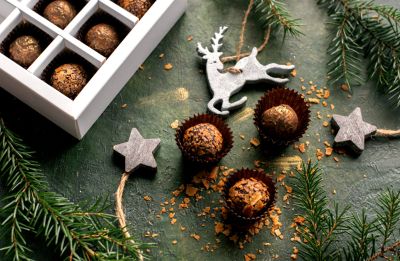 Selbst gemachte Weihnachtspralinen in Papierkapseln und weißer Geschenkbox mit Tannenzweigen