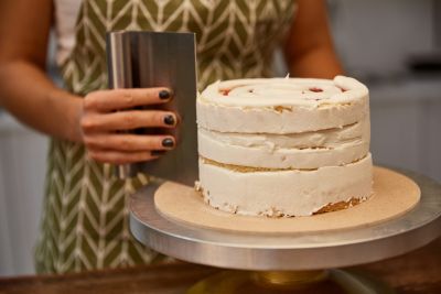 Mit dem Teigschaber wird eine Torte mit Buttercreme eingestrichen
